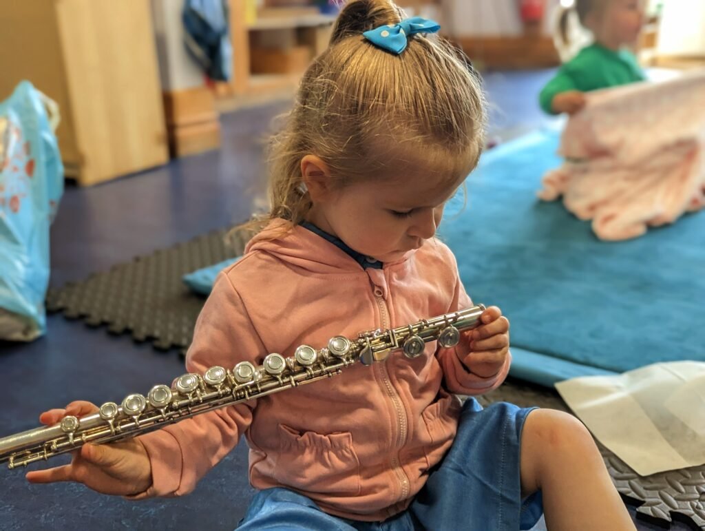 Young girl holds and studies the flute carefully